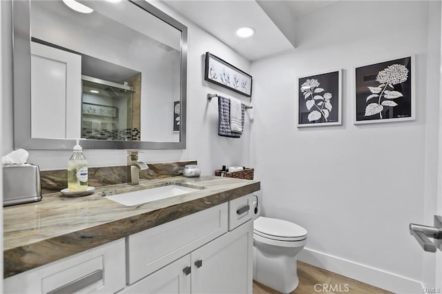 bathroom with toilet, vanity, wood-type flooring, and walk in shower