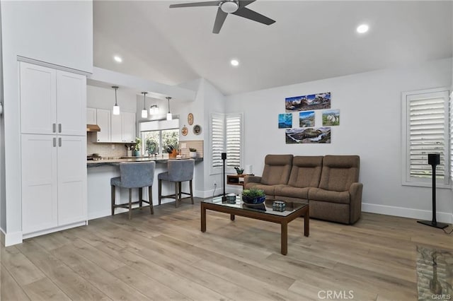 living room featuring ceiling fan, light hardwood / wood-style floors, and vaulted ceiling