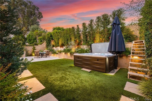 yard at dusk featuring a patio area and a hot tub