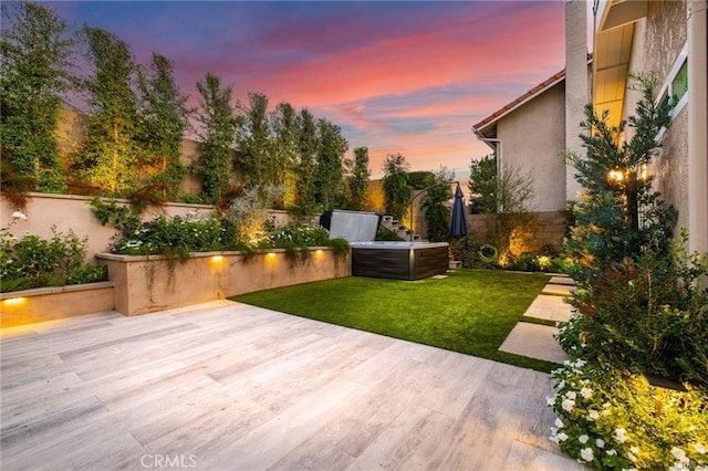 patio terrace at dusk featuring a yard