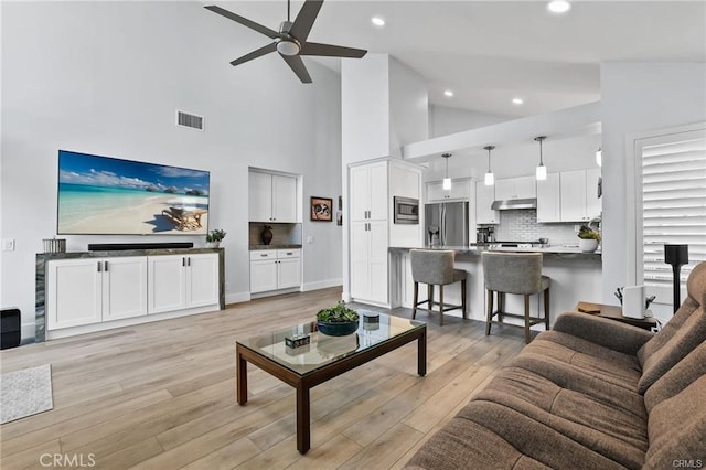 living room featuring high vaulted ceiling, light wood-type flooring, and ceiling fan