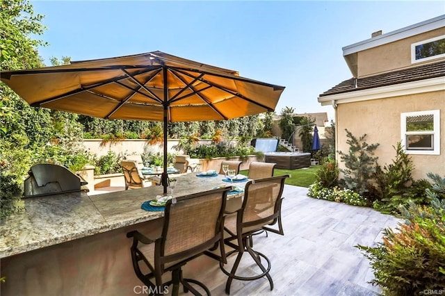 view of patio featuring a bar, a jacuzzi, and area for grilling