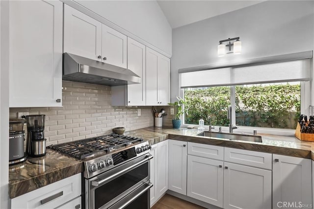 kitchen featuring vaulted ceiling, decorative backsplash, sink, white cabinetry, and range with two ovens