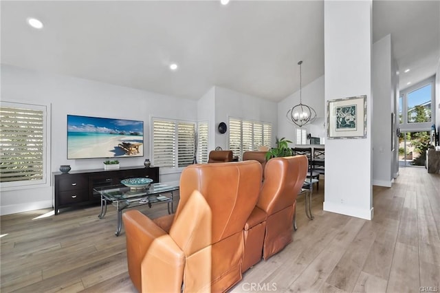 living room with light hardwood / wood-style floors, a chandelier, and vaulted ceiling