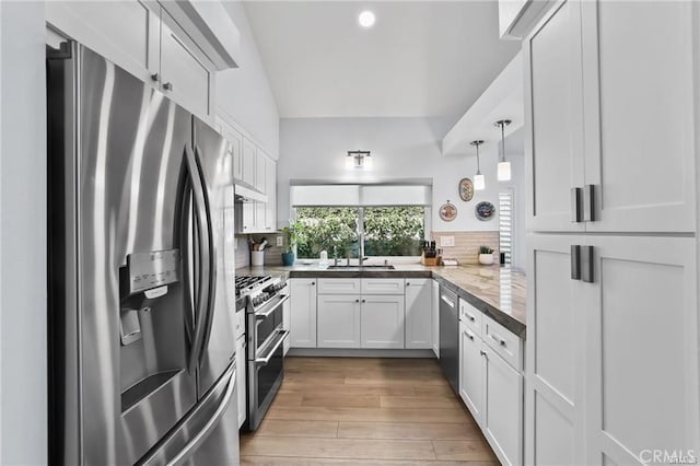 kitchen featuring decorative backsplash, sink, white cabinetry, hanging light fixtures, and stainless steel appliances