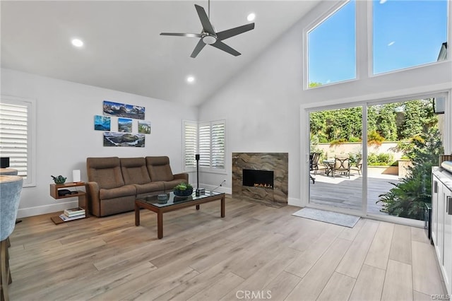 living room with high vaulted ceiling, a wealth of natural light, ceiling fan, and light wood-type flooring