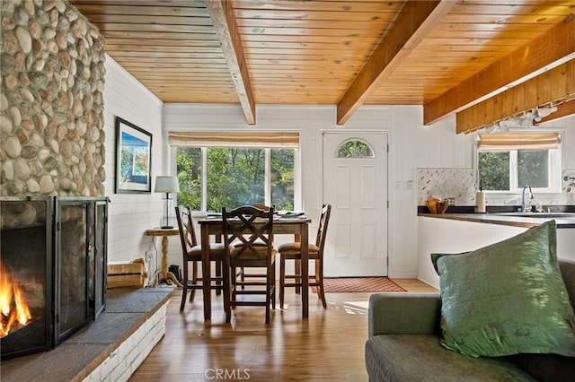 dining space featuring a fireplace, wood-type flooring, sink, beamed ceiling, and wood ceiling