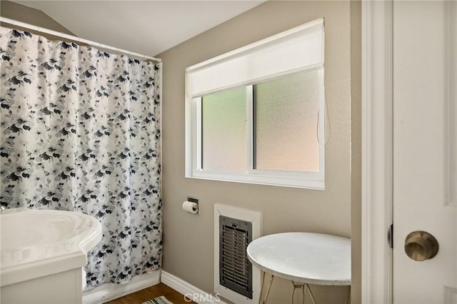 bathroom featuring curtained shower, hardwood / wood-style floors, heating unit, and vaulted ceiling