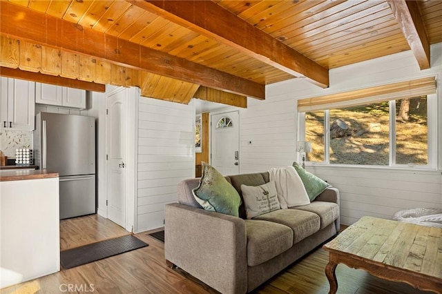 living room featuring beam ceiling, light wood-type flooring, wooden walls, and wooden ceiling