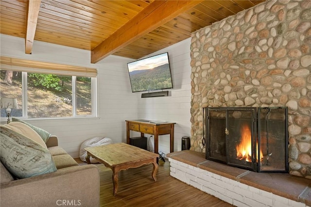 sitting room featuring hardwood / wood-style floors, wooden walls, a stone fireplace, wooden ceiling, and beam ceiling