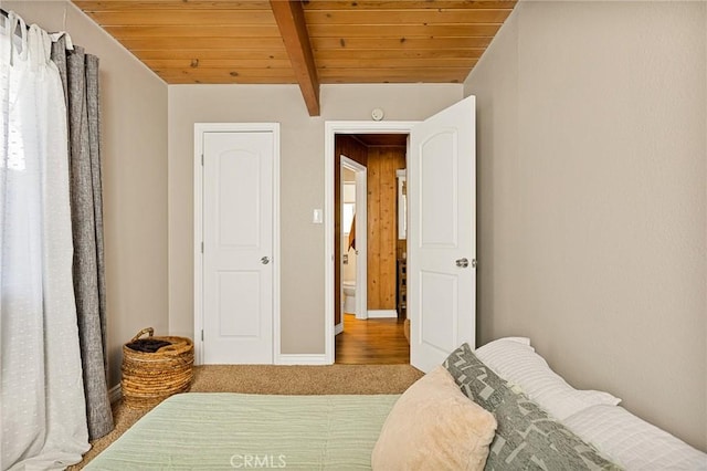 bedroom featuring beam ceiling, carpet floors, and wooden ceiling