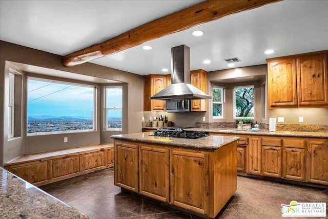 kitchen with island range hood, black gas cooktop, beam ceiling, light stone counters, and a center island