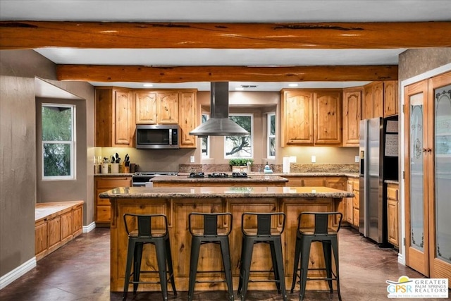 kitchen with appliances with stainless steel finishes, a center island, beamed ceiling, a kitchen breakfast bar, and range hood