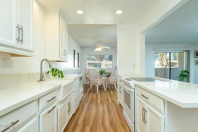 kitchen featuring ceiling fan, white electric range, sink, white cabinetry, and light wood-type flooring