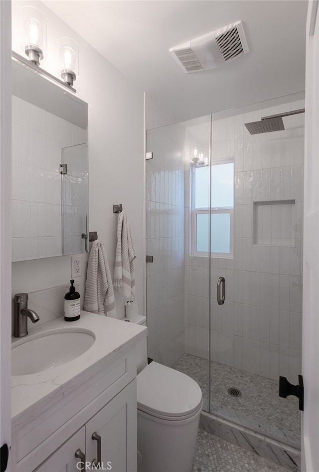 bathroom with a shower with door, toilet, and vanity