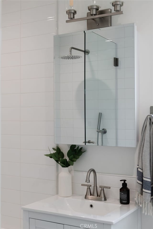 bathroom featuring a shower with shower door, vanity, and decorative backsplash