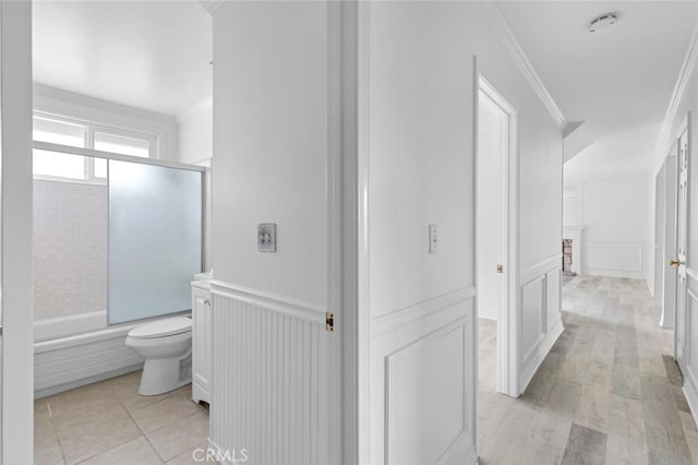 bathroom featuring toilet, tile patterned floors, shower / bath combination with glass door, and ornamental molding