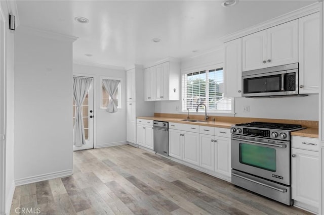 kitchen with stainless steel appliances, ornamental molding, white cabinets, and sink