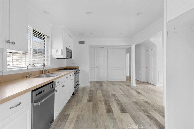 kitchen featuring appliances with stainless steel finishes, sink, white cabinetry, and light hardwood / wood-style flooring