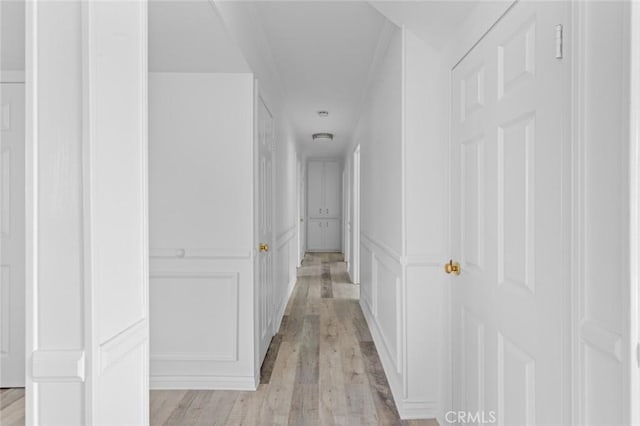 hall with light hardwood / wood-style flooring and ornamental molding