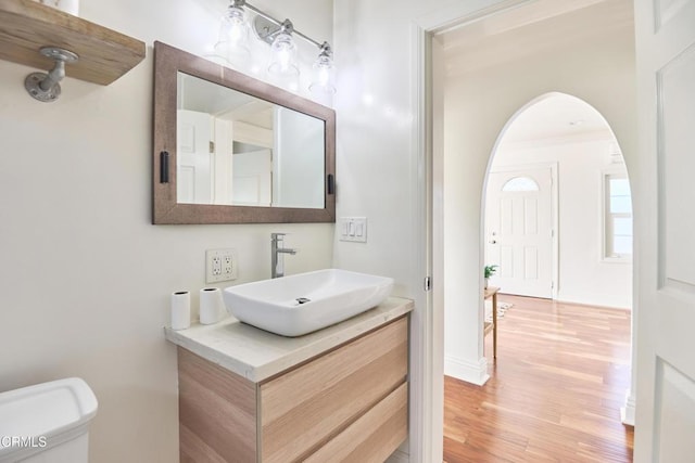 bathroom with toilet, vanity, crown molding, and hardwood / wood-style flooring