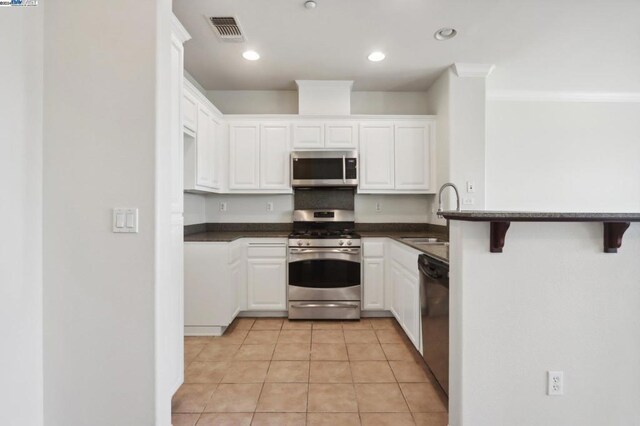 kitchen with a breakfast bar area, white cabinets, sink, and stainless steel appliances