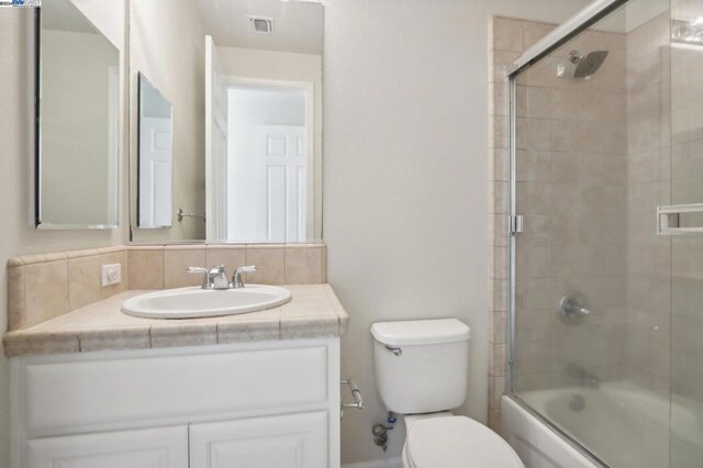 full bathroom featuring toilet, vanity, backsplash, and enclosed tub / shower combo