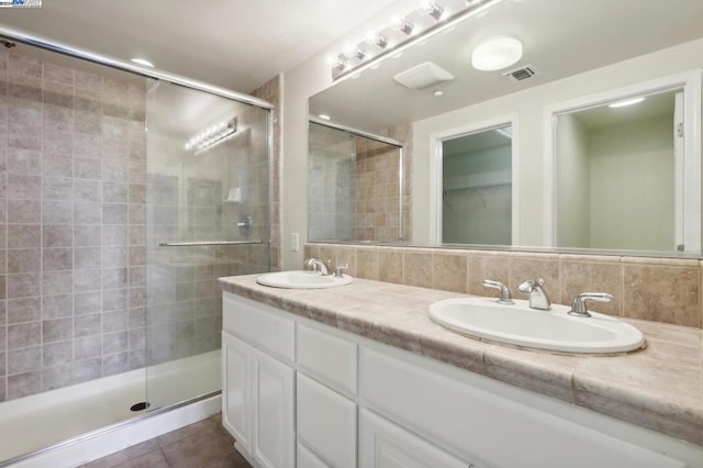 bathroom featuring tile patterned flooring, a shower with door, backsplash, and vanity