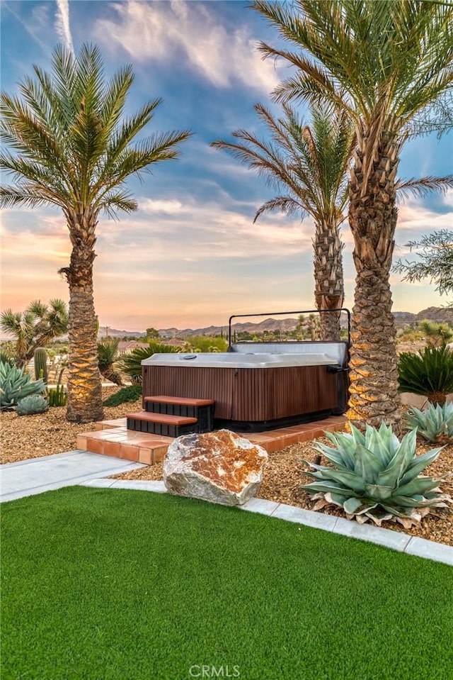 yard at dusk featuring a hot tub