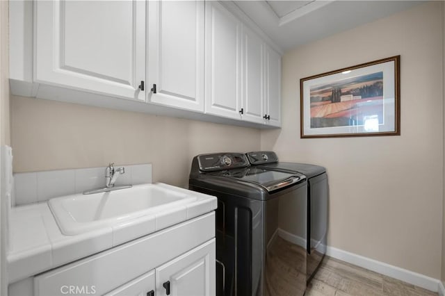 laundry area with washing machine and dryer, cabinets, and sink