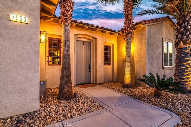 exterior entry at dusk featuring a patio area