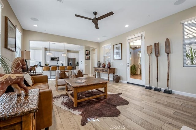 living room featuring light wood-type flooring, ceiling fan, and a healthy amount of sunlight