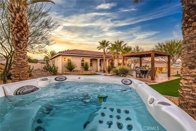 pool at dusk with a patio area, a gazebo, and a hot tub