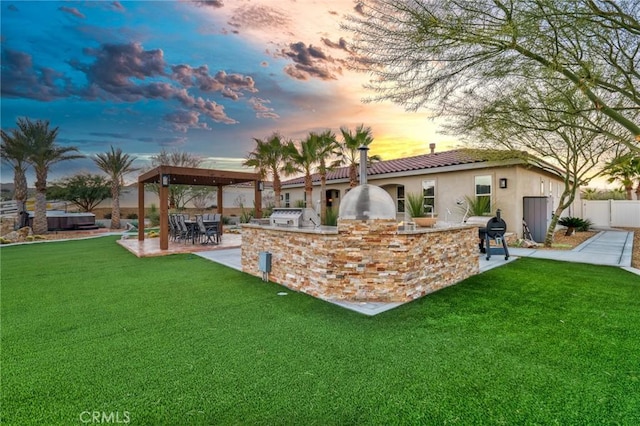 yard at dusk featuring a patio area and an outdoor kitchen