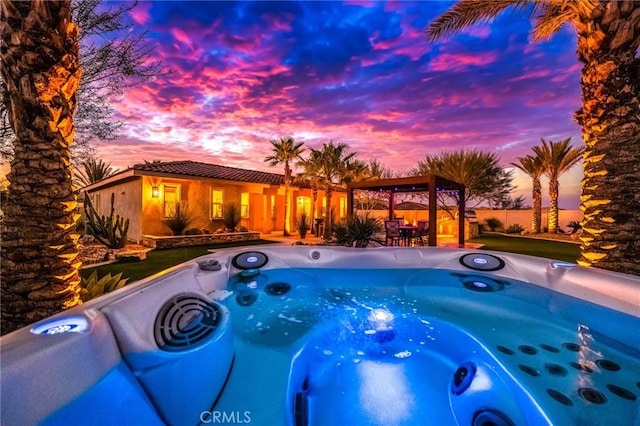 pool at dusk featuring a gazebo and a hot tub