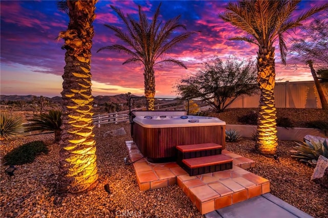 patio terrace at dusk featuring a mountain view, a hot tub, and central AC unit