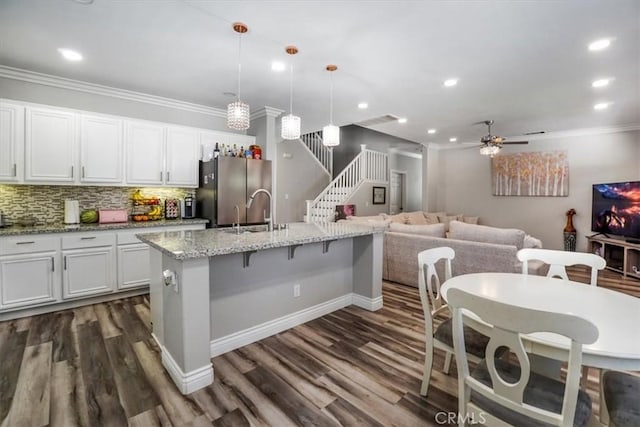 kitchen with decorative light fixtures, white cabinetry, sink, ceiling fan, and a center island with sink