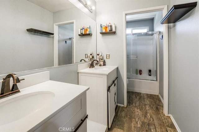 bathroom with hardwood / wood-style floors, combined bath / shower with glass door, and vanity