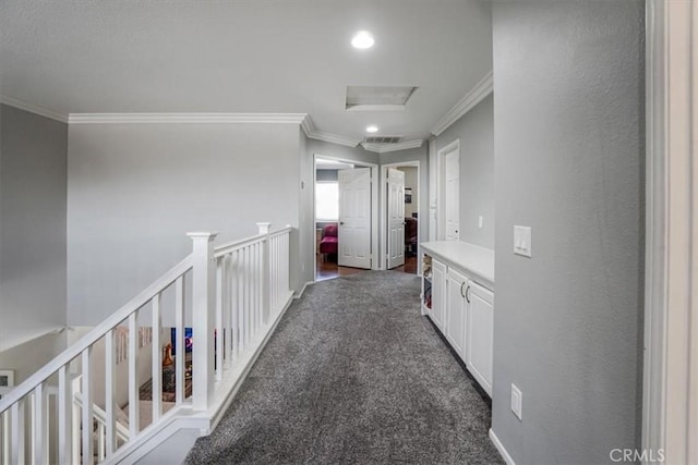 hall with crown molding and dark colored carpet