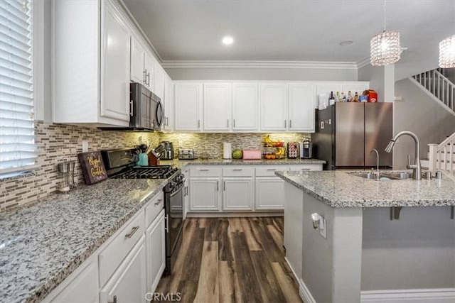 kitchen featuring white cabinetry, black gas range oven, decorative light fixtures, stainless steel refrigerator, and sink