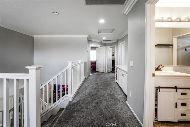 hall with sink, crown molding, and dark colored carpet