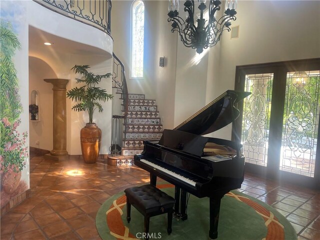 misc room featuring a chandelier, tile patterned floors, a high ceiling, and decorative columns