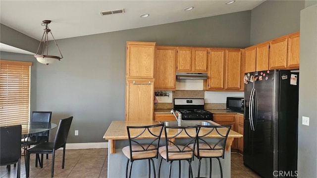 kitchen featuring hanging light fixtures, black appliances, a kitchen island with sink, and tile patterned flooring