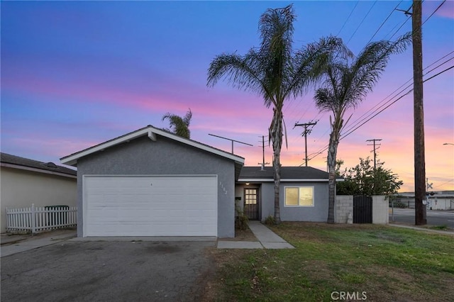 ranch-style house featuring a garage and a yard