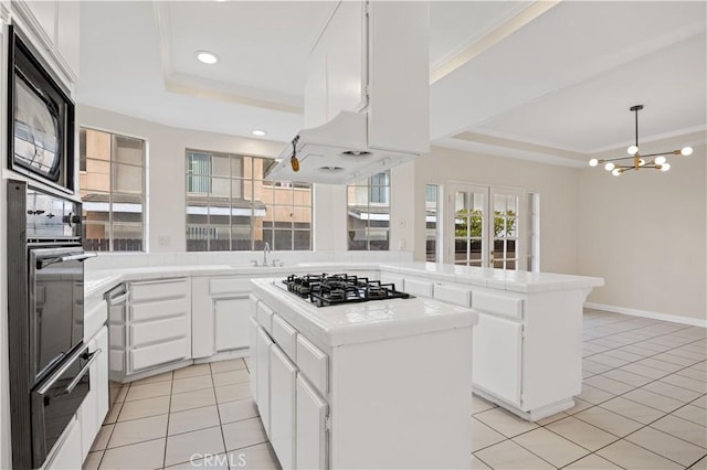 kitchen featuring white cabinets, a center island, wall oven, a raised ceiling, and stainless steel gas stovetop