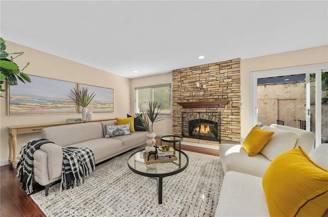 living room featuring a wealth of natural light, a stone fireplace, and hardwood / wood-style floors