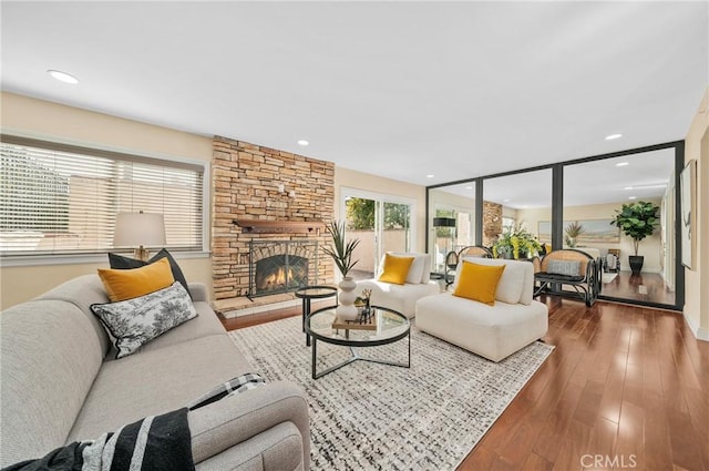 living room with hardwood / wood-style floors and a stone fireplace