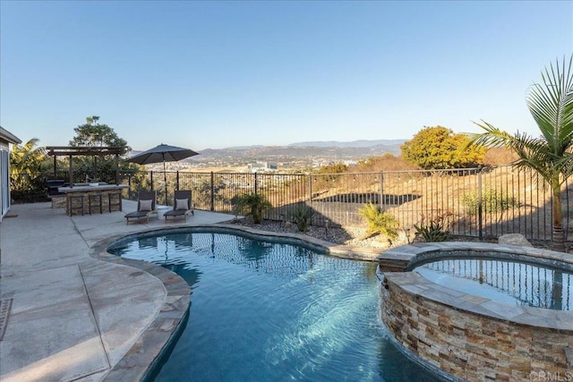 view of pool with a mountain view, an outdoor bar, an in ground hot tub, and a patio area