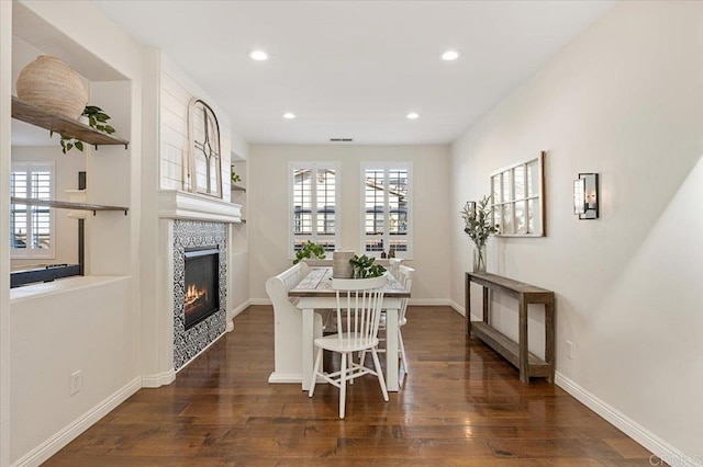 dining area featuring a wealth of natural light, dark hardwood / wood-style flooring, and a fireplace