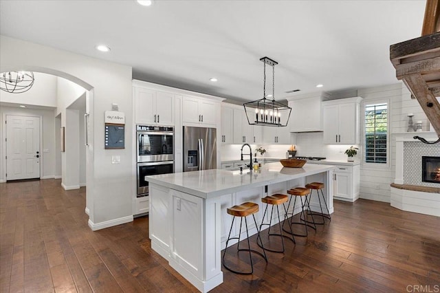 kitchen with appliances with stainless steel finishes, sink, white cabinetry, and an island with sink